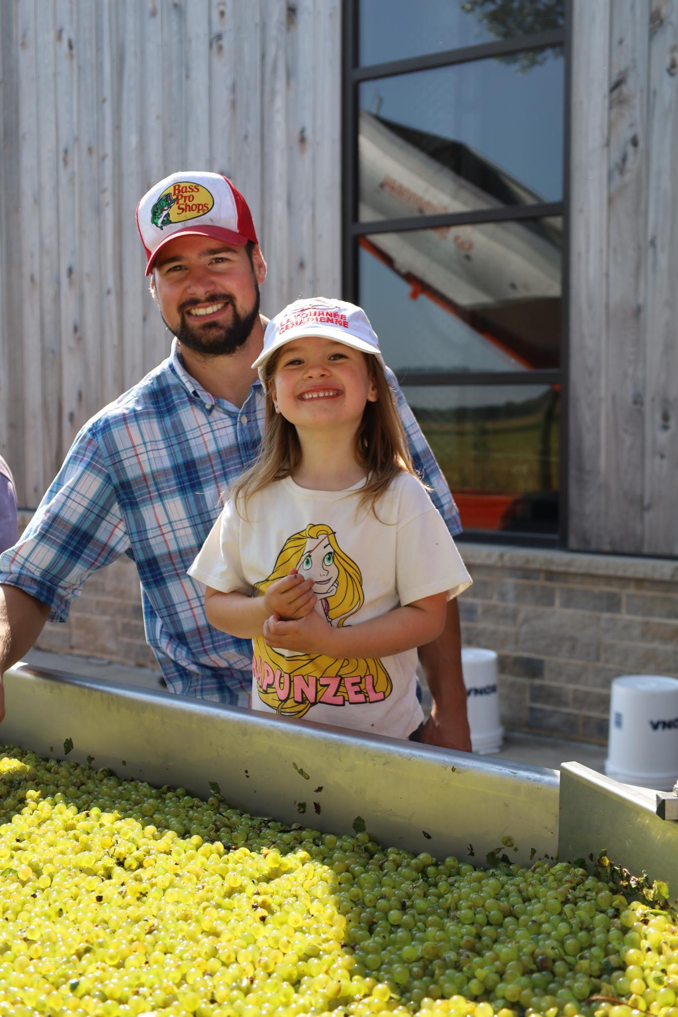 Homme et petite fille souriant à côté des raisins sur le convoyeur